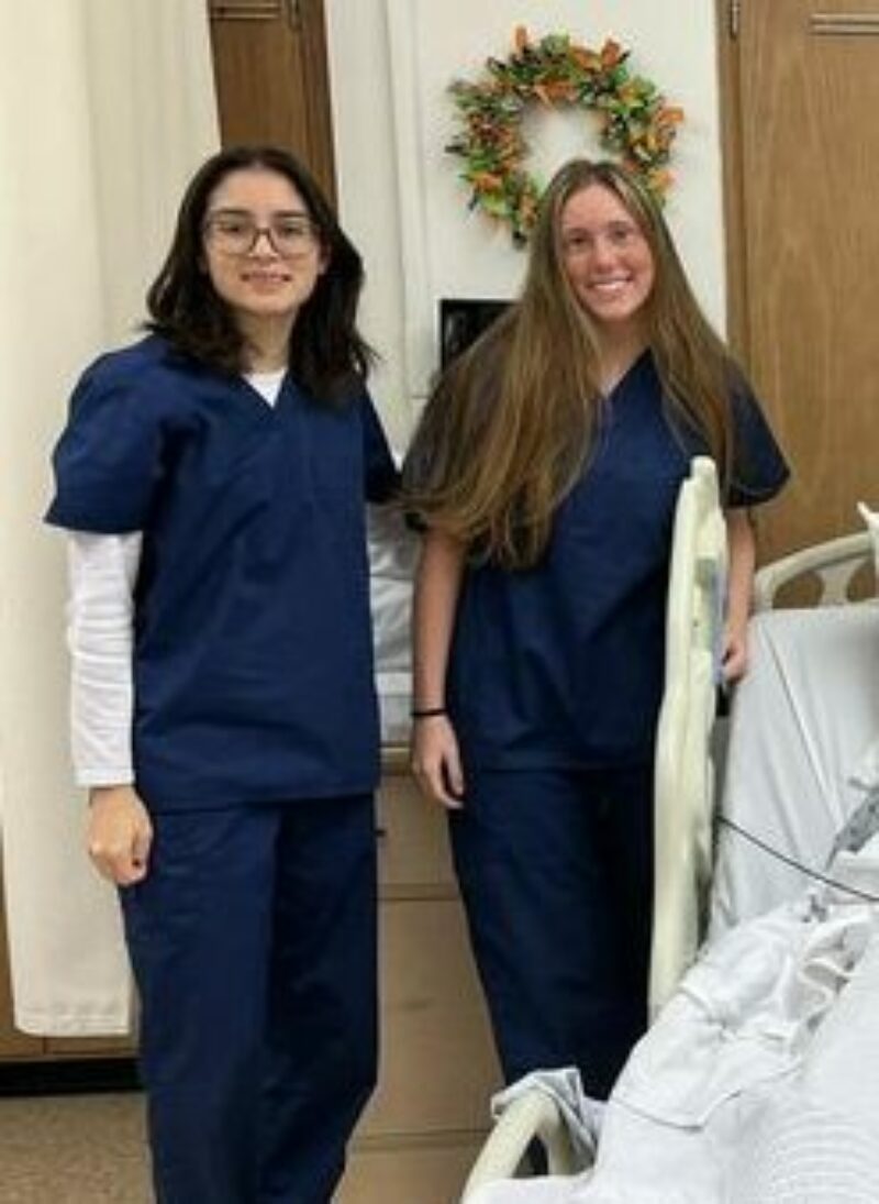 Mercy McCauley students standing next to bed with maniquen