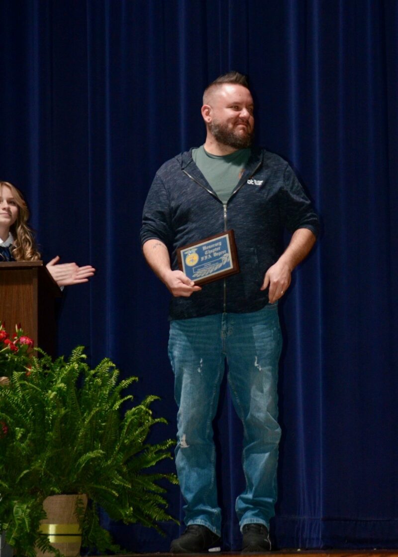 man on stage holding a plaque