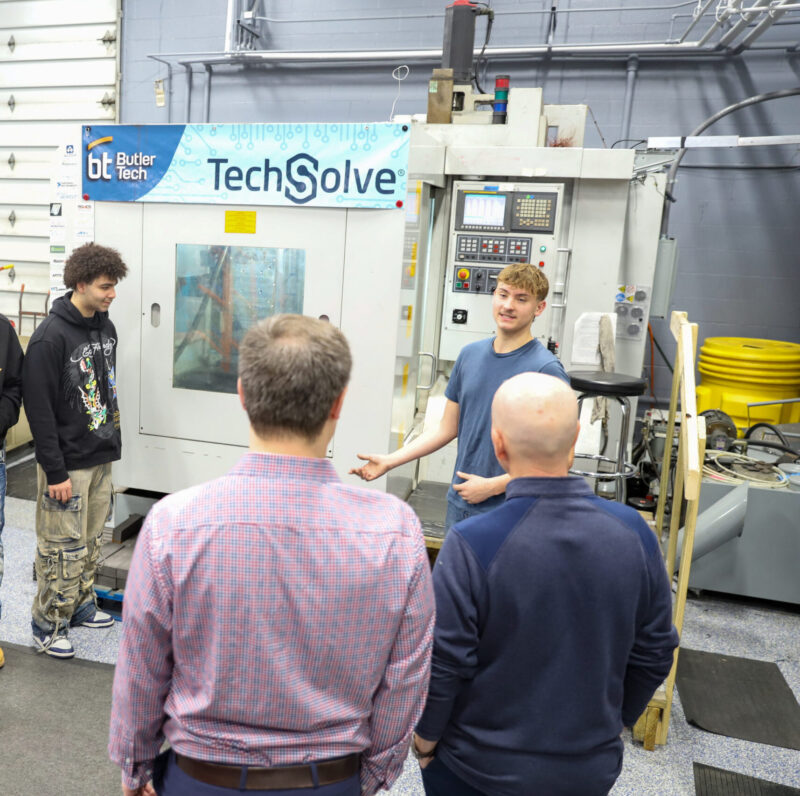 A group of people stands in front of a machine labeled 